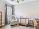 Well-lit Bedroom with neutral tones, modern baby furniture, and a comfortable armchair by the window at 12313 Prairie Plantation Way, Orlando, FL 32824