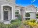 Close-up of front entry with landscaped garden, arched entryway, and gray two car garage at 12313 Prairie Plantation Way, Orlando, FL 32824