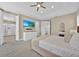 Bright bedroom with ceiling fan, mounted TV, white dresser, and ensuite bathroom with glass shower at 1428 Reunion Blvd, Kissimmee, FL 34747