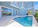 A swimming pool is surrounded by a white patio and a blue house with sliding glass doors at 1428 Reunion Blvd, Kissimmee, FL 34747