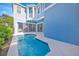 A swimming pool is nestled between a blue house with sliding glass doors and a black metal fence at 1428 Reunion Blvd, Kissimmee, FL 34747