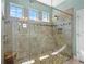 This is a shower with decorative stone tiling, glass enclosure, and natural light through the high transom windows at 1631 Nina Dr, Davenport, FL 33837