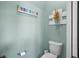 A clean, modern bathroom featuring a toilet, toilet paper holder, and coastal wall art at 1631 Nina Dr, Davenport, FL 33837