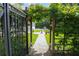 A beautiful backyard pathway with green grass, wooden pergola with flowering vines, and fountain leading to the pool at 202 Acadia Ter, Kissimmee, FL 34747