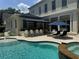 Beautiful backyard pool with waterfalls, a hot tub, covered lanai, outdoor kitchen, and lots of patio space at 202 Acadia Ter, Kissimmee, FL 34747