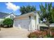 Two-car detached garage with white doors, flower beds, and lush trees at 202 Acadia Ter, Kissimmee, FL 34747