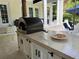 An outdoor kitchen with a pizza oven, granite countertop, cabinets, and pizza with two glasses of wine at 202 Acadia Ter, Kissimmee, FL 34747