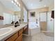 Bright bathroom featuring a double vanity, soaking tub, and glass-enclosed shower with neutral decor and tile at 219 Rosso Dr, Davenport, FL 33837