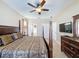 Light bedroom featuring a four-poster bed, ceiling fan, neutral decor, modern TV, and multiple doors at 219 Rosso Dr, Davenport, FL 33837