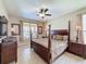 Well-lit bedroom featuring a four-poster bed, ceiling fan, and neutral decor with an exterior view through the window at 219 Rosso Dr, Davenport, FL 33837