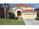 Charming two-story home featuring a red tile roof, lush landscaping, and an attached two car garage at 219 Rosso Dr, Davenport, FL 33837