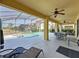 Spacious covered patio with ceiling fans, outdoor dining, and lounge seating overlooking the pool and green space at 219 Rosso Dr, Davenport, FL 33837