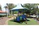 Colorful community playground equipment under a shade structure with lush landscaping surrounding the area at 219 Rosso Dr, Davenport, FL 33837