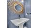 Stylish powder room with a pedestal sink, decorative mirror, and elegant blue wall paint at 2287 Park Maitland Ct, Maitland, FL 32751