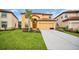 Inviting two-story home with a well-manicured lawn, palm tree, and a two-car garage and red tile roof at 2630 Tranquility Way, Kissimmee, FL 34746