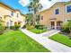 Exterior view of the condos featuring lush green grass, sidewalks and tropical landscaping at 2736 Oakwater Dr, Kissimmee, FL 34747