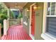 Close-up of a inviting front porch with red wood planking, white railings and charming lighting at 2810 Elizabeth Ave, Orlando, FL 32804