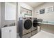 Functional laundry room with modern washer and dryer, utility sink, and ample storage space at 2821 Columbus Ave, Clermont, FL 34715