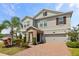 Two-story home featuring a manicured lawn, lovely stone accents, and a brick driveway at 2901 Harvest Hill Ln, Orlando, FL 32824