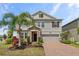 Two-story home featuring a manicured lawn, lovely stone accents, and a brick driveway at 2901 Harvest Hill Ln, Orlando, FL 32824