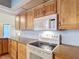 Galley kitchen showcases wooden cabinetry, cooktop, and microwave, offering a functional cooking space at 3110 Short Leaf Pine Ct, Kissimmee, FL 34746