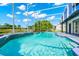 A screened-in pool sparkles under a blue sky with manicured landscaping and mature trees at 3170 Zaharias Dr, Orlando, FL 32837