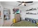 Neutral-toned bedroom featuring a ceiling fan, TV, dark shelves, and an adjoining room at 3425 Middlebrook Pl, Harmony, FL 34773