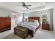 Comfortable main bedroom with tray ceiling, hardwood furniture, and natural light at 3425 Middlebrook Pl, Harmony, FL 34773