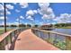 Charming boardwalk leading to a covered gazebo on a serene lake with lush greenery and a clear sky at 352 Alicante Ct, Davenport, FL 33837