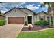 Charming home with a brick driveway, manicured lawn, beautiful shrubs, and a two-car garage at 352 Alicante Ct, Davenport, FL 33837