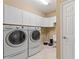 Well-equipped laundry room with front-loading washer and dryer, ample cabinet space, and neutral tile flooring at 352 Alicante Ct, Davenport, FL 33837