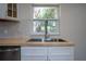 Close-up shot of kitchen sink and backsplash, wooden countertop, and ample natural light at 453 E Jessup Ave, Longwood, FL 32750