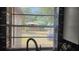 Kitchen window view of a lush backyard through horizontal blinds at 4760 Danzig Ct, Orlando, FL 32811