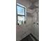 Close up of shower with marble tiling, black honeycomb floor, and products on inset shelf at 4760 Danzig Ct, Orlando, FL 32811