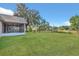 Backyard with a well-maintained lawn, mature trees, and partial view of home's screened-in patio at 4885 Meadow Dr, St Cloud, FL 34772