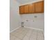 Practical laundry room with tiled floor, wooden wall cabinets, and convenient connections for appliances at 4885 Meadow Dr, St Cloud, FL 34772