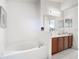 Bright bathroom featuring a double sink vanity, large mirror, and tub at 5577 Sycamore Canyon Dr, Kissimmee, FL 34758