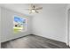Bright, minimalist bedroom with gray wood-look floors and a window with neighborhood views at 5642 Chukar Dr, Orlando, FL 32810