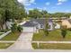 Single story home with a gray exterior, attached garage, green lawn and mature trees at 5642 Chukar Dr, Orlando, FL 32810