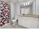 Bathroom featuring large vanity, tub and shower combo with geometric shower curtain at 7184 Oakmoss Loop, Davenport, FL 33837