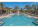 Large community pool surrounded by palm trees and lounge chairs offering a resort-style living experience at 7184 Oakmoss Loop, Davenport, FL 33837