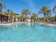 Expansive community pool offers a relaxing retreat surrounded by palm trees and comfortable lounge seating at 7184 Oakmoss Loop, Davenport, FL 33837