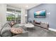 Cozy living room with a large gray sofa, flat screen tv, and access to the outdoor patio at 7184 Oakmoss Loop, Davenport, FL 33837