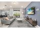 Comfortable living room with a gray sofa, a mounted TV, and sliding glass doors to the patio at 7184 Oakmoss Loop, Davenport, FL 33837