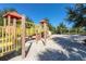 Community playground featuring slides and climbing equipment on a sand base with mature shade trees at 7184 Oakmoss Loop, Davenport, FL 33837