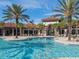 Resort-style pool with clear water, palm trees, and buildings in the background at 7184 Oakmoss Loop, Davenport, FL 33837