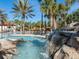 Water cascading off rock structure into beautiful community pool featuring palm trees and resort amenities at 7184 Oakmoss Loop, Davenport, FL 33837