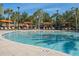 Large community pool featuring palm trees, lounge chairs, shade cabanas, and a shallow entry point at 7184 Oakmoss Loop, Davenport, FL 33837