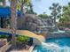 Resort-style pool featuring a slide and waterfall cascading into the clear water at 7184 Oakmoss Loop, Davenport, FL 33837
