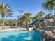Community water park with a slide and waterfalls surrounded by tropical landscaping and palm trees at 7184 Oakmoss Loop, Davenport, FL 33837